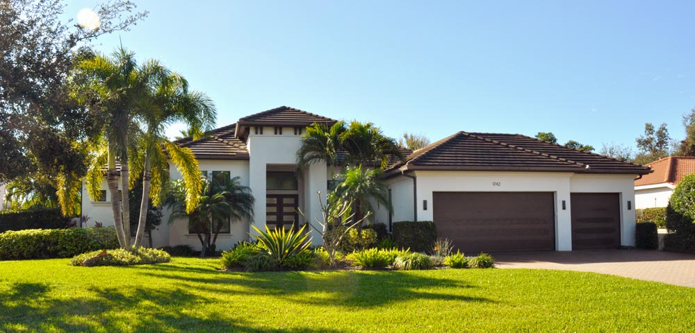 Street view of contemporary coastal style single family home with brown roof and white walls