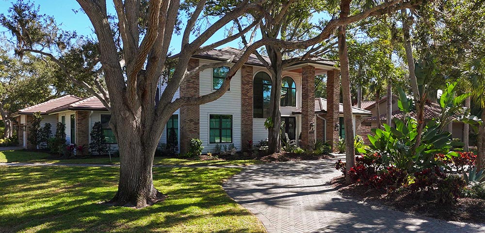 Street view of transitional Florida estate style single family home with brick corners and columns