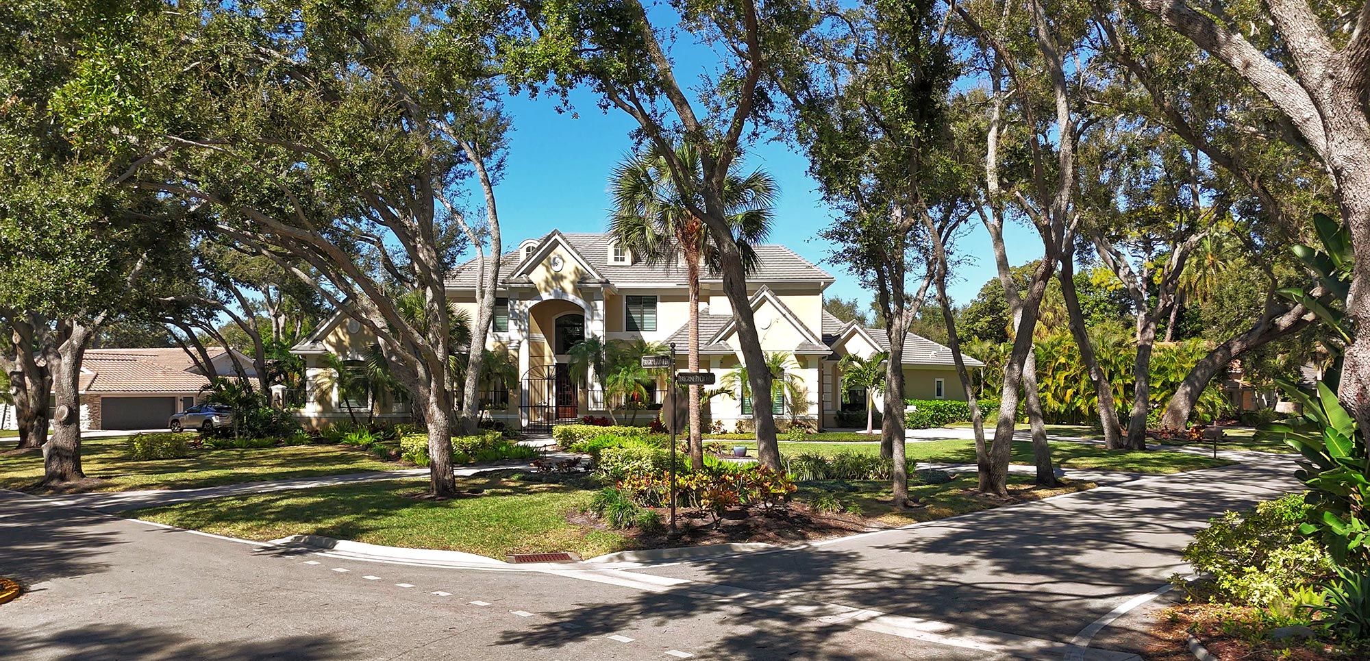 Street view of single family home with two story grand entry and surrounded by many live oak trees